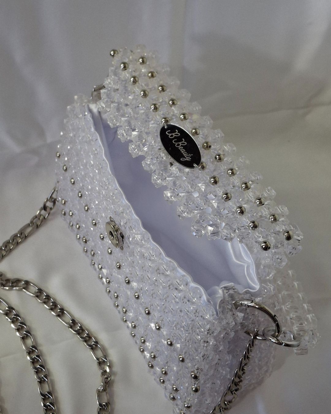 White beaded headband with silver accents on a white background