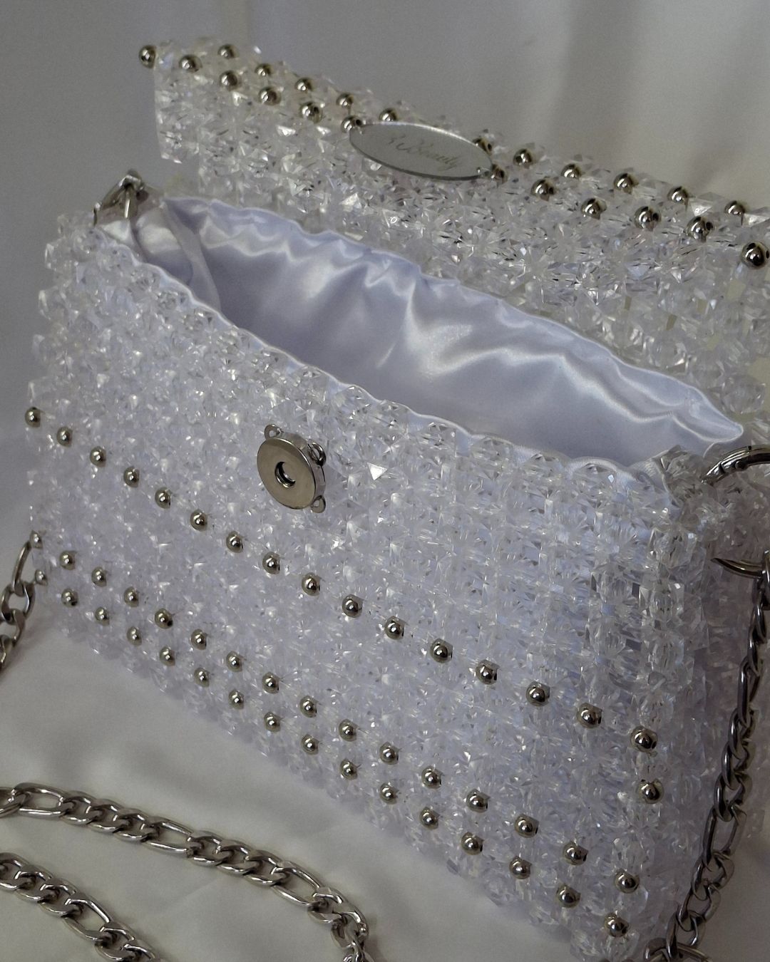 Sparkly handbag with silver beads and chain strap on a white background