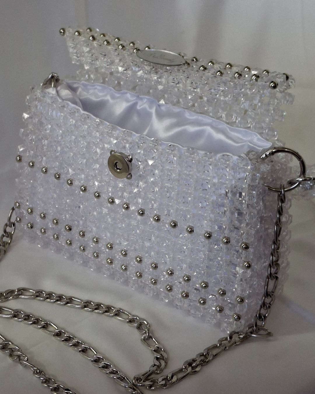 Sparkly handbag with silver chain strap on a white background